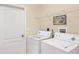 Functional laundry room with white washer and dryer, upper shelving and a door at 4980 Whispering Oaks Dr, North Port, FL 34287
