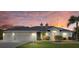 Charming single-story home featuring a lush lawn, mature palms, and a tranquil sunset at 52 Fairway Rd, Rotonda West, FL 33947