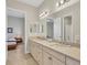 Dual vanity bathroom with light cabinetry, mirrors, and neutral decor at 11897 Hunters Creek Rd, Venice, FL 34293