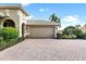 Two-car garage with a beige door and a brick paved driveway at 134 Savona Way, North Venice, FL 34275