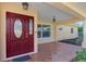 Front porch with a terracotta tile floor and a burgundy door at 225 Firenze W Ave, Venice, FL 34285