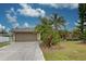 Tan house with attached garage and a spacious front yard at 23102 Madelyn Ave, Port Charlotte, FL 33954