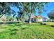 Expansive backyard with mature trees, lush grass, and a view of the home's back side at 2331 Harrier Way, Nokomis, FL 34275