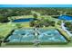 Four tennis courts with surrounding hedges and golf course view at 2331 Harrier Way, Nokomis, FL 34275