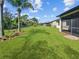 Expansive backyard featuring lush green grass, a black metal fence, and a screened lanai for outdoor enjoyment at 2501 Sherman Oak Dr, North Port, FL 34289