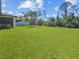Expansive, well-manicured backyard with lush green lawn, mature trees, and secure fencing at 2501 Sherman Oak Dr, North Port, FL 34289