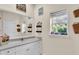 Bathroom vanity with white cabinets, mirror, and window providing natural light at 3200 Rowland Dr, Punta Gorda, FL 33980