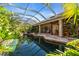 Spacious pool with a large screened enclosure, lush tropical landscaping, and a stone patio at 3200 Rowland Dr, Punta Gorda, FL 33980