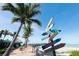 Beachfront pathway with palm trees and colorful directional signage leading to a pier and sandy beach at 3730 Cadbury Cir # 105, Venice, FL 34293