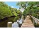 Long wooden dock stretching over a tranquil waterway at 405 Pinebrook Cres # 5, Venice, FL 34285