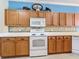 Kitchen with oak cabinets, white appliances, and tile backsplash at 5255 Athens Way, Venice, FL 34293