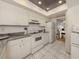 White kitchen with dark countertops, white appliances, and tile floor at 533 Parkdale Mews # 533, Venice, FL 34285