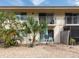 Back patio with outdoor seating beneath palm trees, screened lanai at 533 Parkdale Mews # 533, Venice, FL 34285