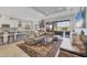 Open-concept living space with a large sofa, kitchen bar, dining area, and a seamless flow to the outdoor patio at 5584 Cantucci St, Nokomis, FL 34275
