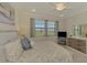 Bright bedroom with large windows overlooking greenery, TV and decor at 10039 Crooked Creek Dr # 203, Venice, FL 34293