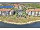 Aerial view of residential condos with community pool surrounded by palm trees and landscaping near lake at 17118 Vardon Ter # 202, Bradenton, FL 34211