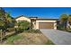 Single-story home with brown garage door, landscaping, and a paved driveway at 1836 W Isles Rd, Port Charlotte, FL 33953