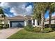 Single-story home with a gray garage door, landscaping, and a brick driveway at 19279 Jacinda St, Venice, FL 34293