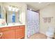 Guest bathroom with orange vanity, white countertop, and decorative shower curtain at 20100 Ragazza Cir # 101, Venice, FL 34293