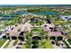 Aerial view of a gated community with a large clubhouse, pool, tennis courts, and lush landscaping at 20100 Ragazza Cir # 101, Venice, FL 34293