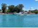 Boat navigating calm waters near a shoreline with trees and parked cars at 20100 Ragazza Cir # 101, Venice, FL 34293