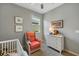 Bright bedroom with crib, dresser, and comfortable armchair at 2049 Mesic Hammock Way, Venice, FL 34292