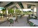 Outdoor seating area with tables and chairs under a covered patio overlooking lush green space at 26069 Norman Dr, Englewood, FL 34223