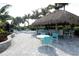 Relaxing outdoor area with a thatched tiki hut, seating area, and tropical landscaping at 26069 Norman Dr, Englewood, FL 34223