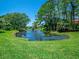 Serene pond with fountain, lush landscaping, and mature trees at 3667 Yellow Pine Ct # 149, Sarasota, FL 34238