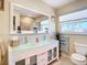 Bright bathroom with a modern glass vanity, dual sinks, and a large mirror reflecting natural light at 4 Windsor Dr, Englewood, FL 34223