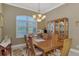 Formal dining room with chandelier, wooden table, and large window with plantation shutters at 5372 Oakmont Ct, North Port, FL 34287