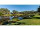 Scenic backyard with green grass, serene pond, and waterfront homes at 5856 Helicon Pl, Sarasota, FL 34238