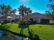Tranquil backyard with lush grass, mature trees, and a screened-in patio overlooking the water at 5856 Helicon Pl, Sarasota, FL 34238