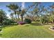 Expansive backyard with lush green lawn, mature trees and gorgeous landscaping at 589 Pond Willow Ln, Venice, FL 34292