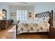 Inviting bedroom featuring a bed with tropical-themed bedding, hardwood floors, and shuttered windows at 589 Pond Willow Ln, Venice, FL 34292