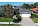 Charming home featuring a well-manicured lawn, tile roof, and paver driveway leading to a two-car garage at 589 Pond Willow Ln, Venice, FL 34292