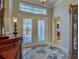 Bright foyer with decorative glass double doors, transom window, tile flooring, and entry to home office at 589 Pond Willow Ln, Venice, FL 34292