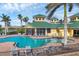 Community pool with lounge chairs, palm trees, and the community center in the background at 6370 Falcon Lair Dr, North Port, FL 34287