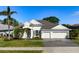 Single-story home with a three-car garage, landscaped yard, and palm trees at 709 Petrel Way, Venice, FL 34285