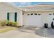 White garage door with green shutters and landscaping at 904 Addington Ct # 104, Venice, FL 34293