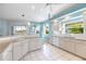 Bright kitchen features tiled flooring, white cabinets, and a view of the lanai through a window at 1307 Highland Greens Dr, Venice, FL 34285