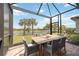 Covered patio with a dining table showcasing scenic lake views and tropical palm trees at 13510 Esposito St, Venice, FL 34293