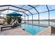 Enclosed pool and lanai with lake view, lounge chairs, and umbrella at 287 Cassano Dr, Nokomis, FL 34275