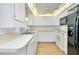 White kitchen with black appliances and light wood floor at 441 Circlewood Dr # M6, Venice, FL 34293