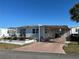 Front exterior view of a mobile home with a covered carport and landscaping at 708 Roma Rd, Venice, FL 34285