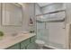 Bright bathroom showcasing a glass-enclosed shower and mint vanity with modern fixtures at 9855 Haze Dr, Venice, FL 34292