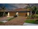 Two-car garage with paver driveway and lush landscaping at 12313 Amica Loop, Venice, FL 34293