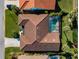 Aerial view of home with terracotta tile roof, lush lawn, and screened pool at 1678 Quail Lake Dr, Venice, FL 34293