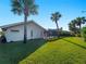 A spacious backyard featuring tropical landscaping, a covered patio, and ample green space for outdoor activities at 1678 Quail Lake Dr, Venice, FL 34293