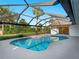 Beautiful screened-in pool area with tropical landscaping and clear blue sky at 1678 Quail Lake Dr, Venice, FL 34293